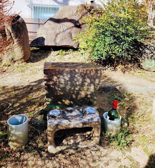 Okiku's grave surrounded by offerings, with a large stone in the background saying "Okikutsuka"