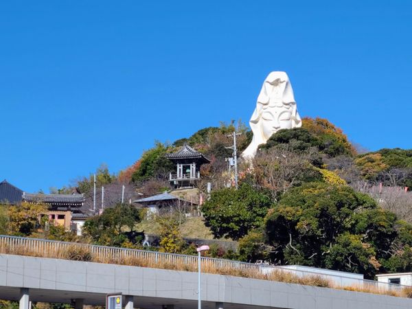 Huge white Ofuna Kannon statue poking out of the mountain forest