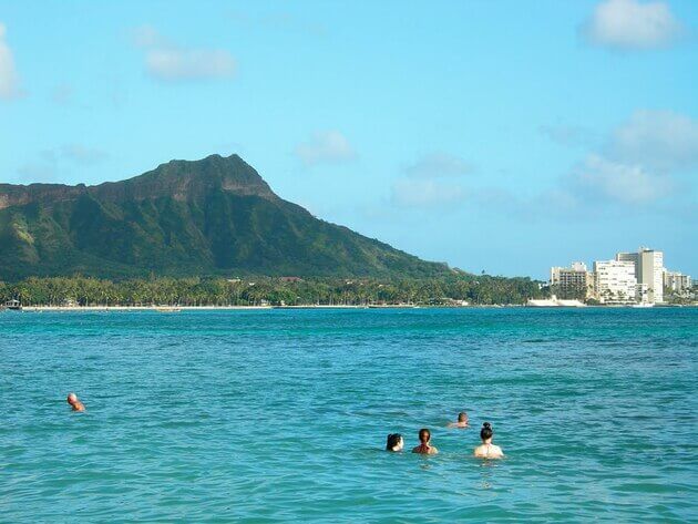 Waikīkī Beach with people bobbing in the water, and Diamond Head in the background
