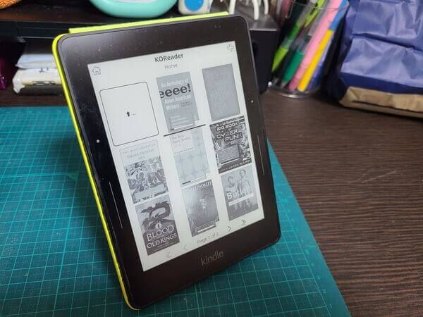 The Kindle Voyage with custom OS KOReader installed and displaying rows of my eBooks