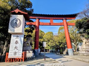 Large red shrine torii gate with a large sign and symbol for Tsurugaoka Hachimangu