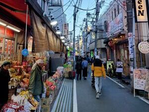 Market street in Ōfuna with food stalls, restaurants, and other shops. People are crowded along the street in front of the shops