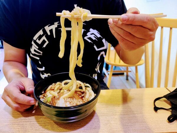 Daikon holding up a bunch of super thick udon noodles from a bowl.