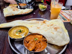 Lunch plate with a huge nan and two small bowls of brown curry