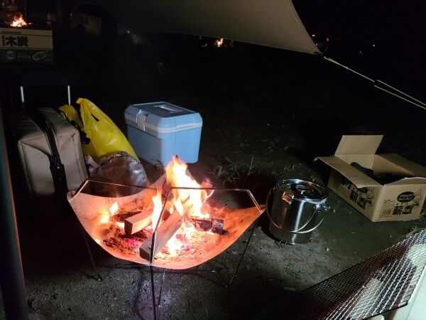 A bright wooden campfire in the center of a dark picture.