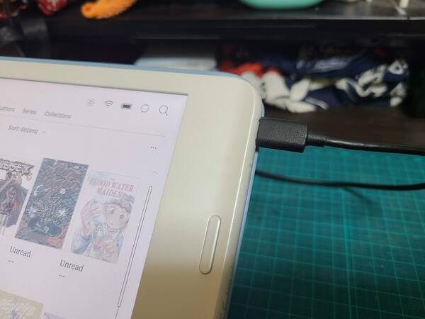 A USB-C cable plugged into the side of the Kobo Libra Colour while it is standing up in its case