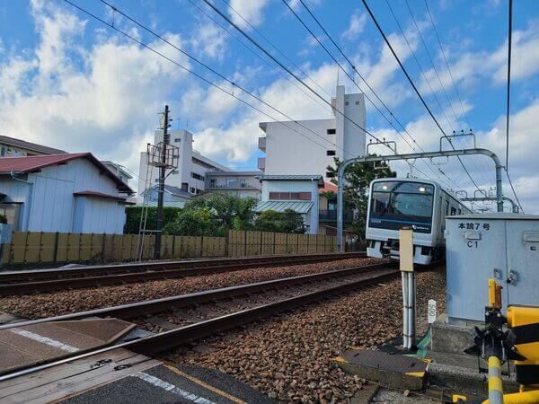The Odakyu Enoshima local train coming down the tracks at a railroad crossing