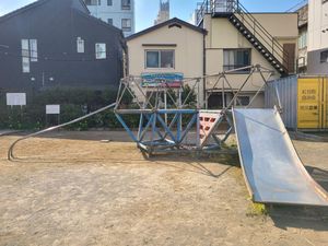 A bare metal jungle gym with a large slide, bars on the side to climb up, and a metal platform held up with faded plastic